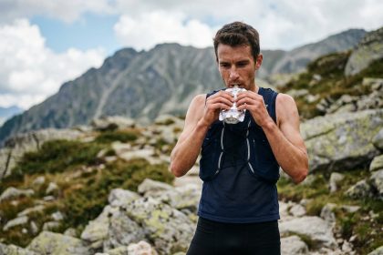 Coureur de trail consommant une purée énergétique maison en montagne lors d'une longue sortie